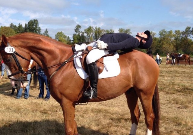 Highlight, a very patient OTTB, lets trainer Devin Robel practice her limbo skills for next year's Area VII Trainer Limbo Challenge. Photo by Terri Niles.